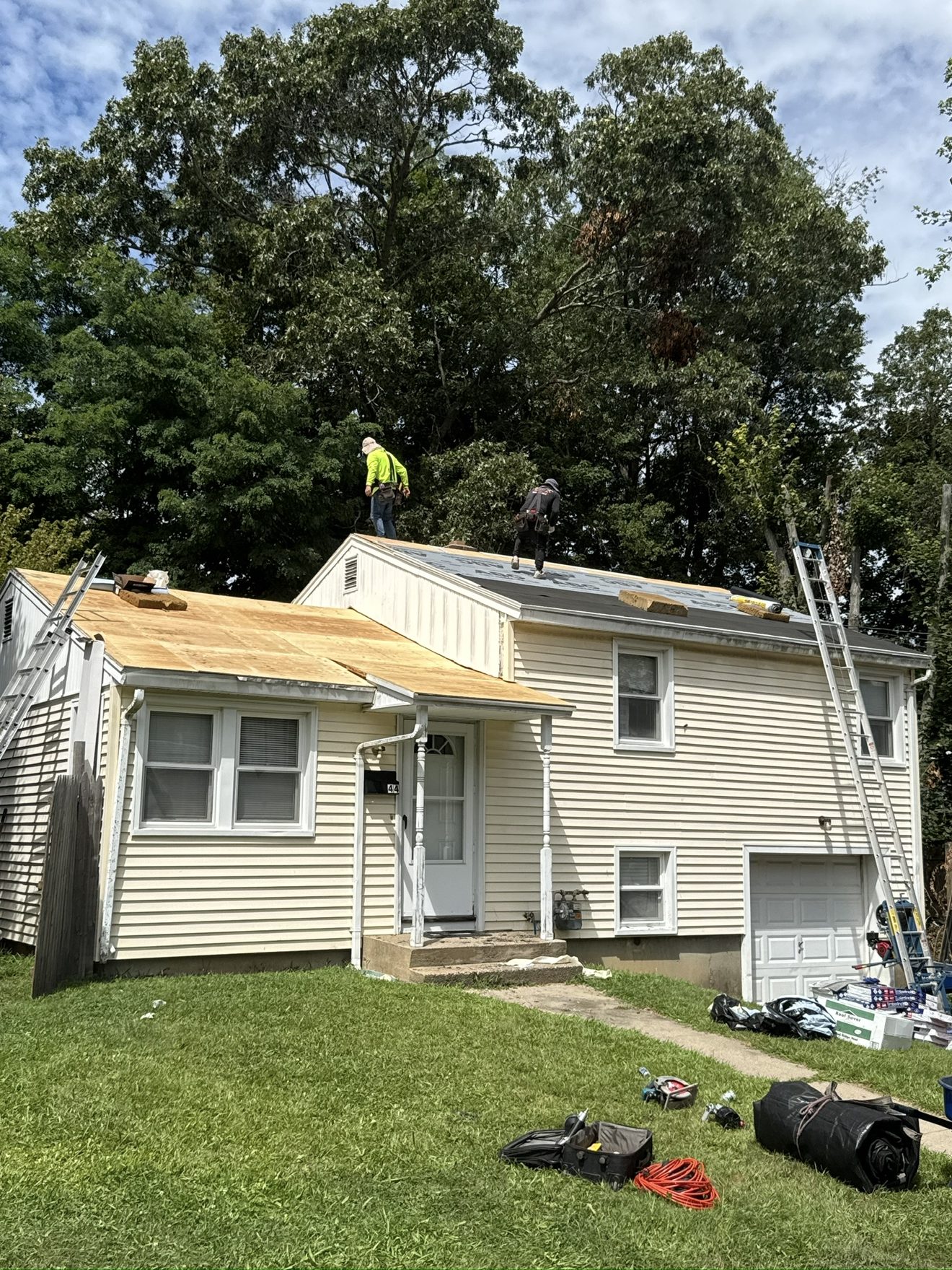 Roofing crew member working on plywood roof deck installation overlooking a Connecticut neighborhood