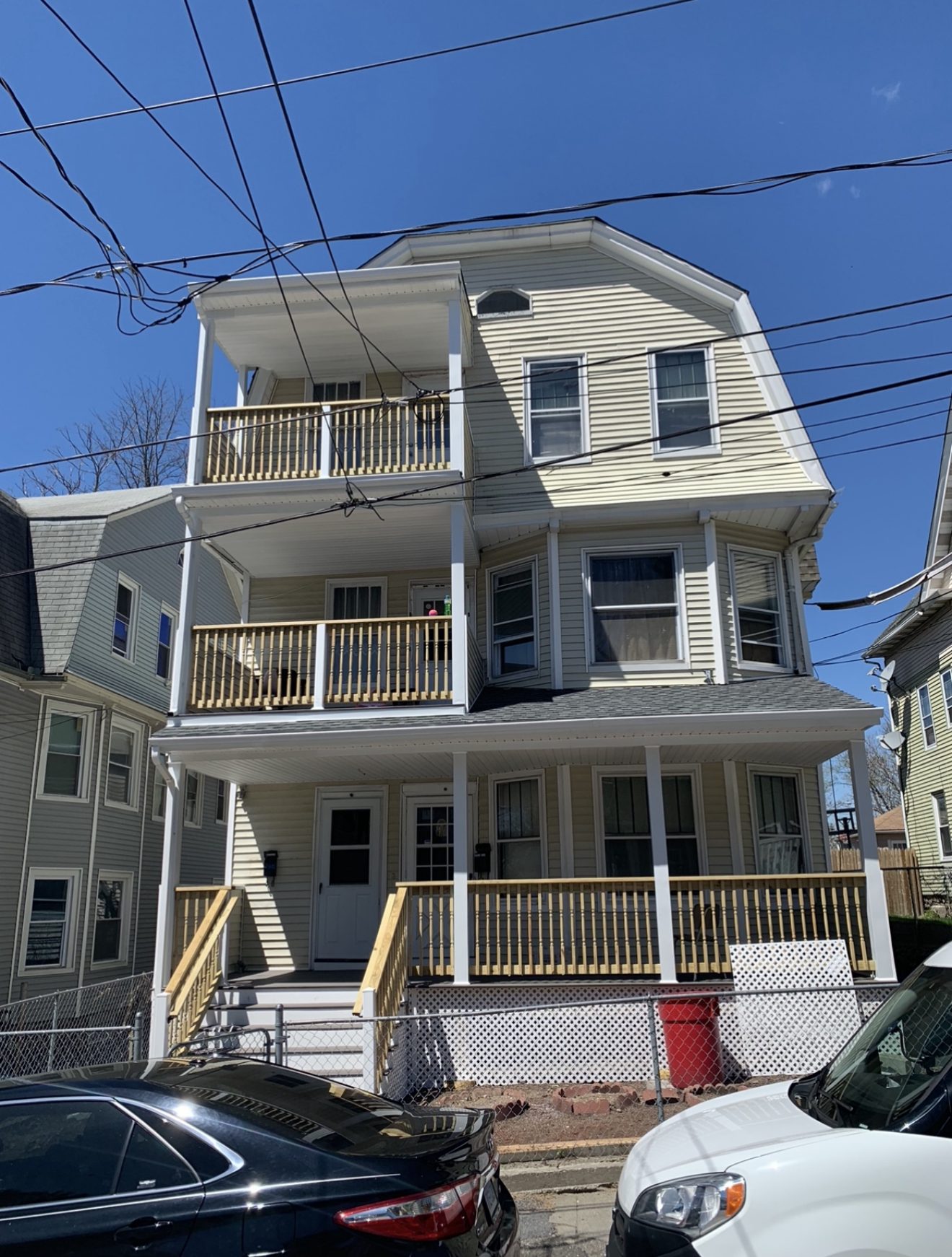 Finished triple-decker apartment building with brand new wood porches, railings, and stairs on all three levels