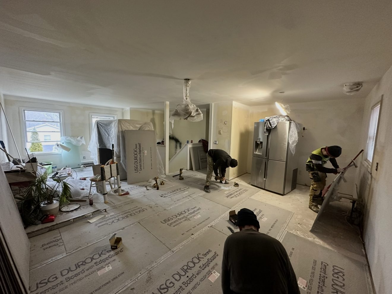Next Gen Construction crew members working on an interior remodel, installing cement backer board