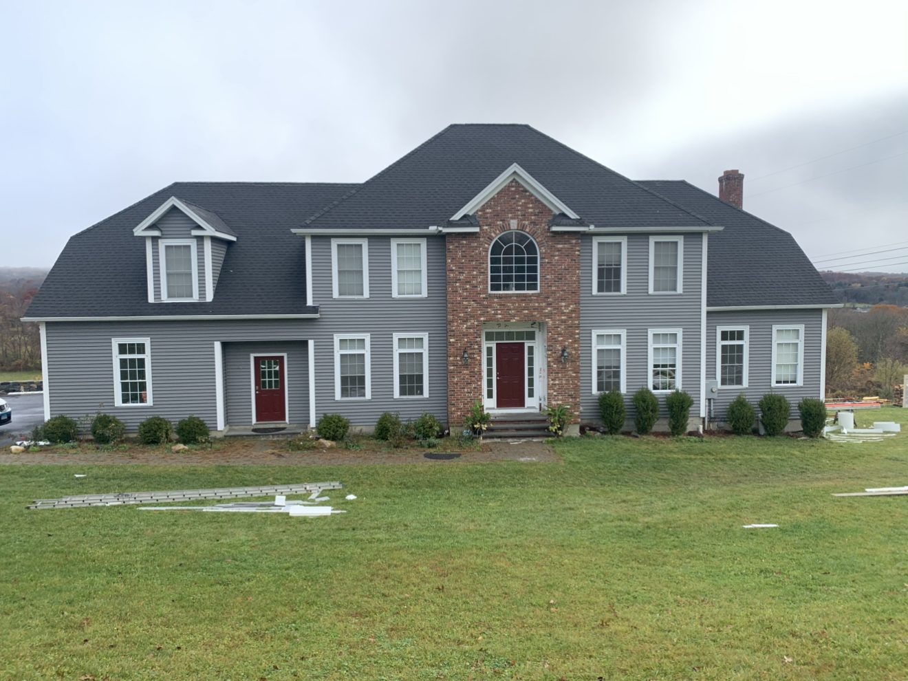 Completed gray siding installation on a large Connecticut estate home with red front door