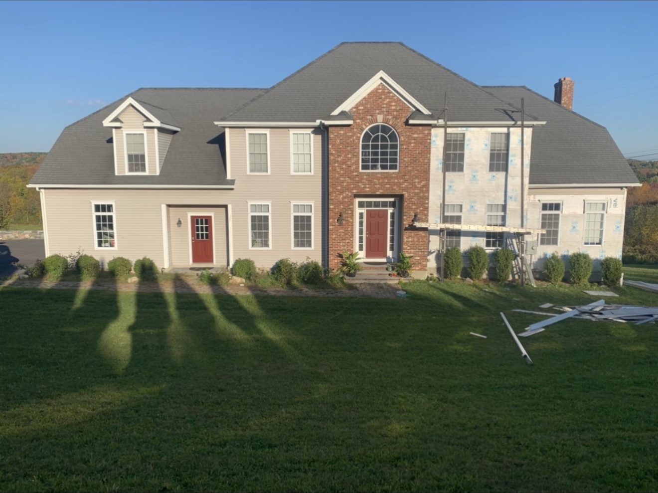 Before — large estate home wrapped in Tyvek house wrap mid-siding install