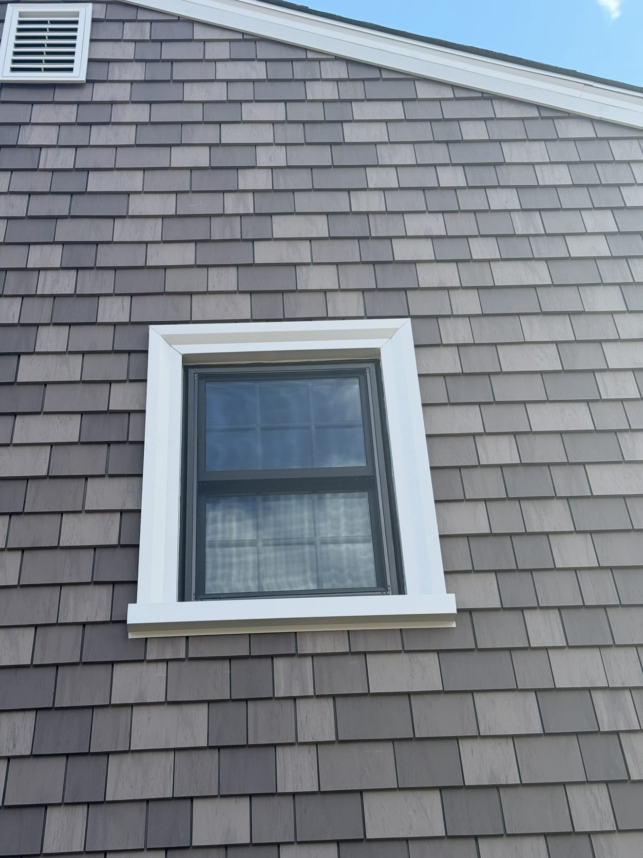 Close-up detail of cedar shingle siding and crisp white window and gutter trim